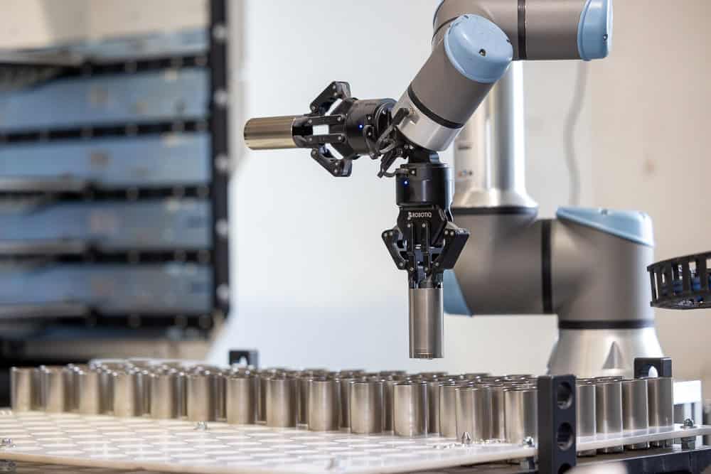 FPX250416110619_1000px a robotic arm with a long cylindrical object on a conveyor belt