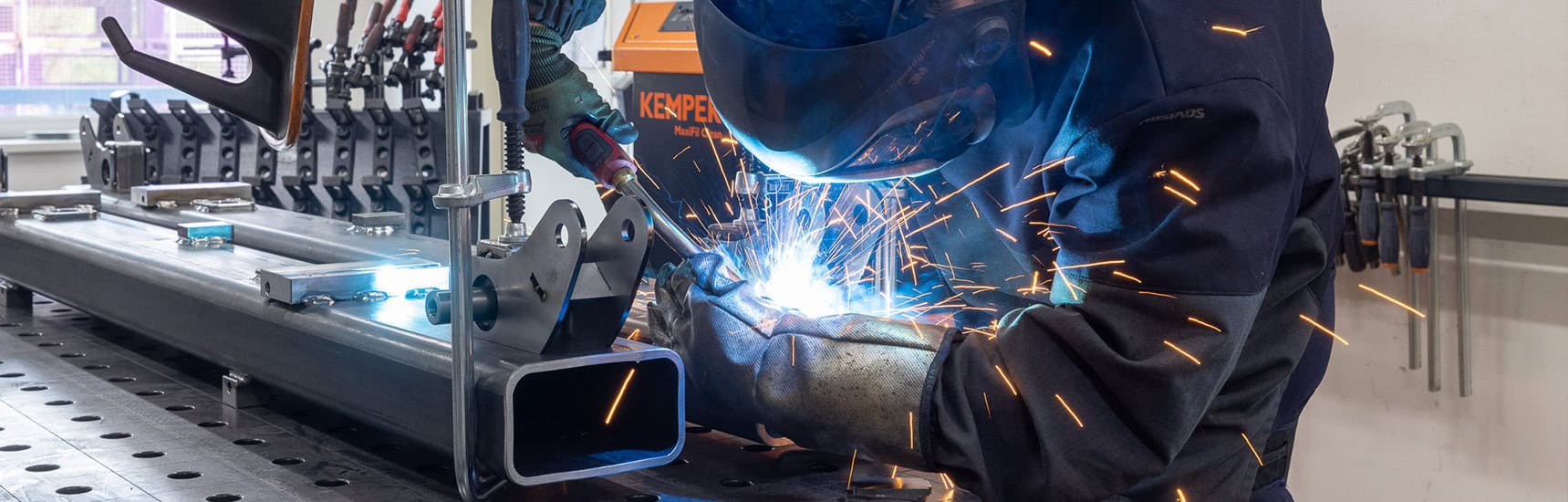 A man welding metal pipes in a factory.